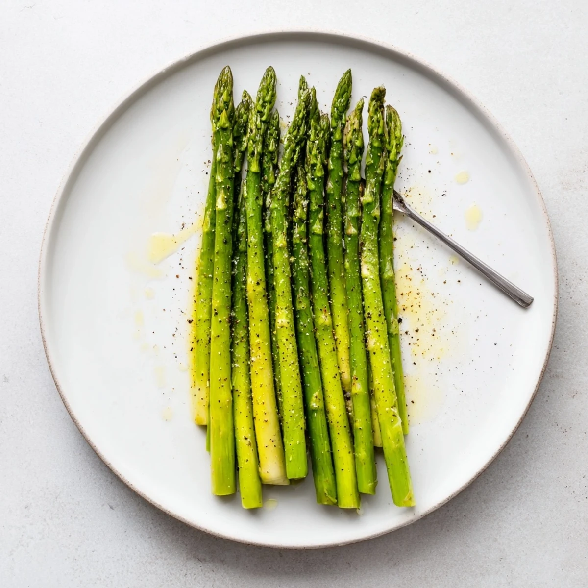 Steamed Asparagus piled on white platter, bright green, glistening with lemon
