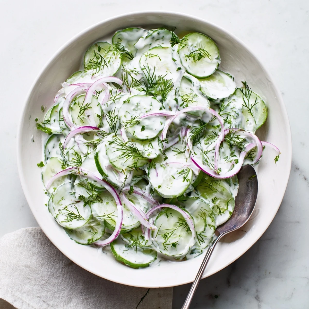 Fresh Greek yogurt cucumber salad with crisp sliced cucumbers in a creamy white dressing bowl