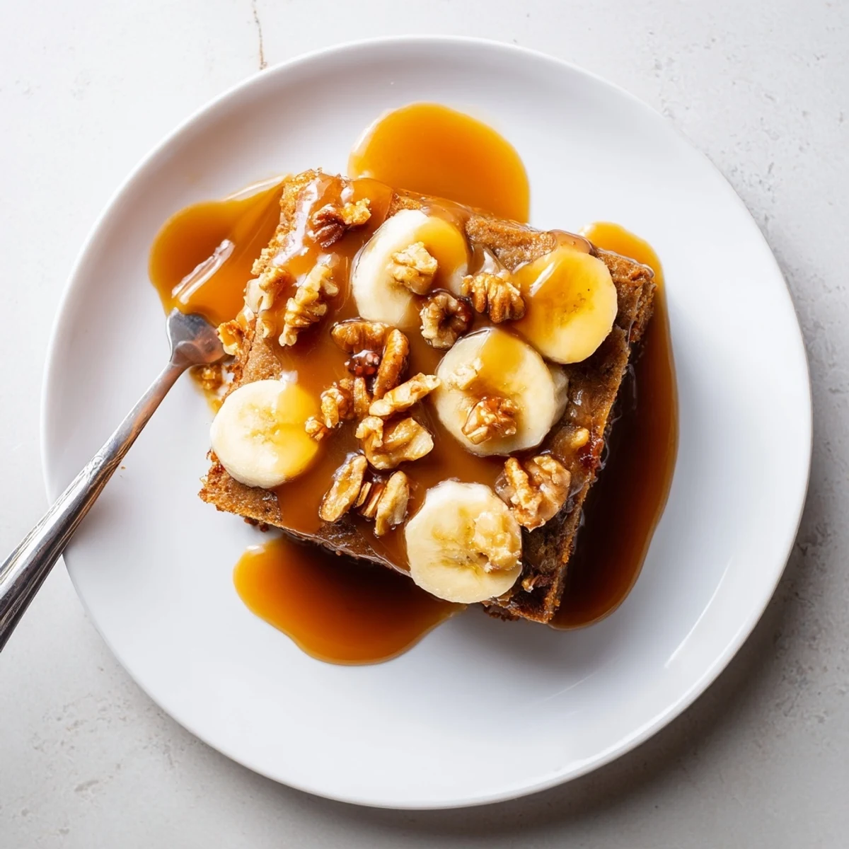 Moist banana cake topped with glossy salted caramel and fresh banana slices