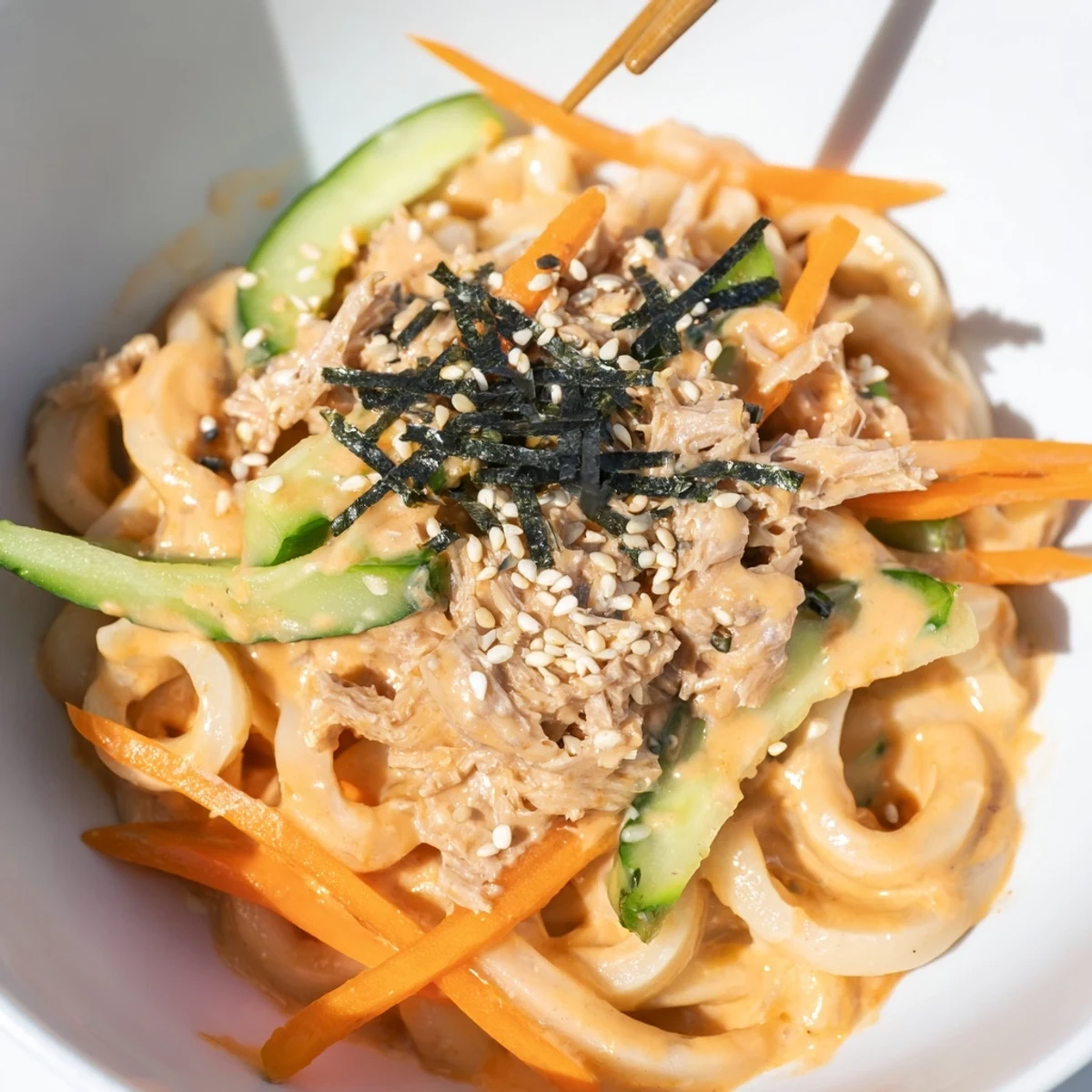 Thick chewy udon noodles coated in spicy sriracha mayo sauce with tender flaked tuna and sesame seeds