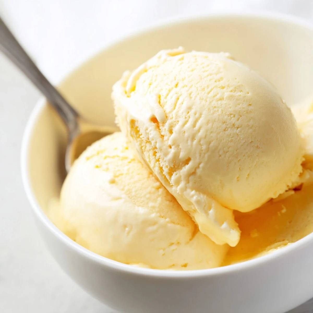 Homemade vanilla ice cream recipe showing smooth pale yellow custard being churned in an electric maker