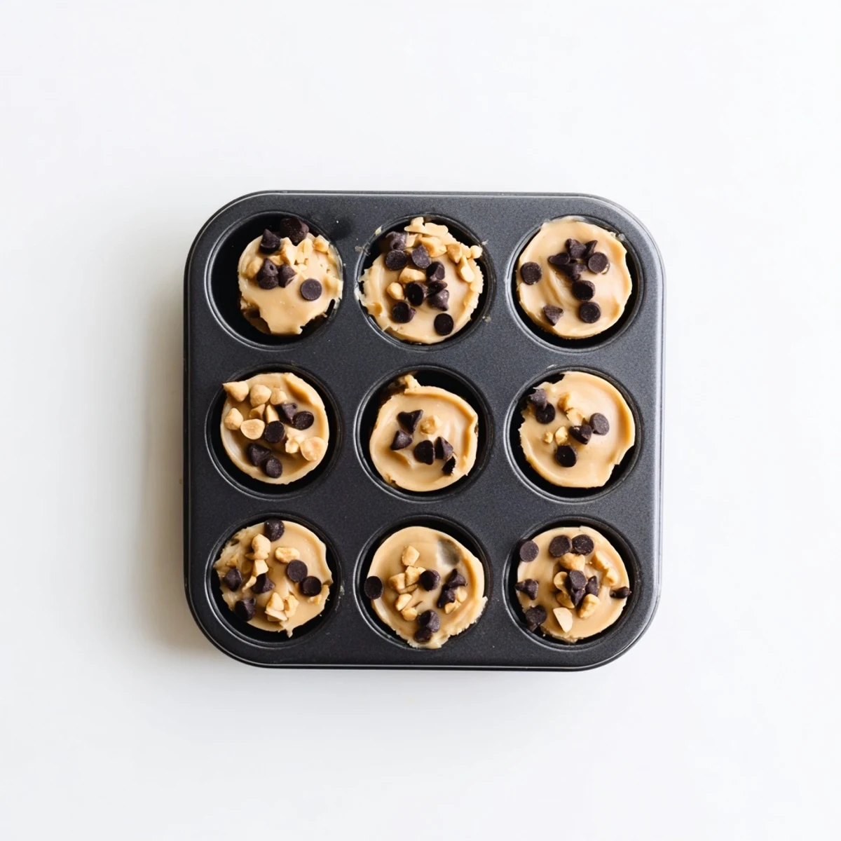 Creamy high protein frozen peanut butter Greek yogurt bites topped with melted dark chocolate drizzle and crushed peanuts in a mini muffin tin