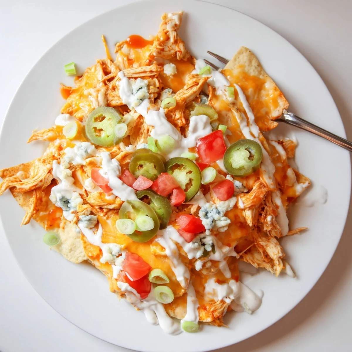 Late night game day Buffalo Chicken Nachos on a baking sheet, ranch drizzled