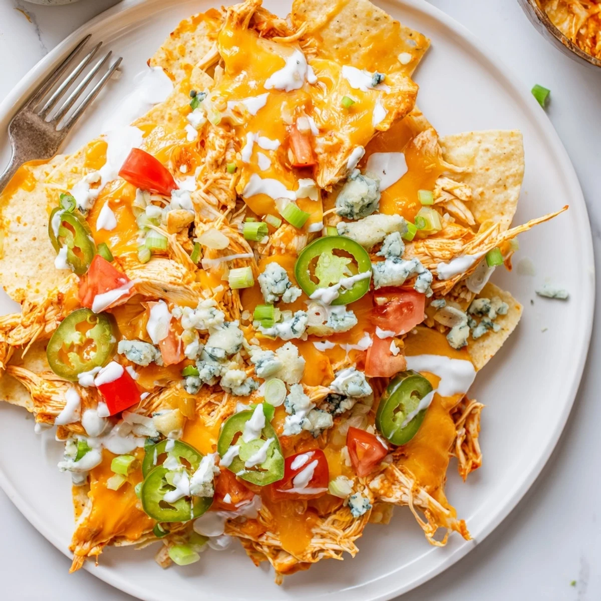 Crispy tortilla bed holding Buffalo Chicken Nachos, melted cheddar, diced tomatoes, green onions