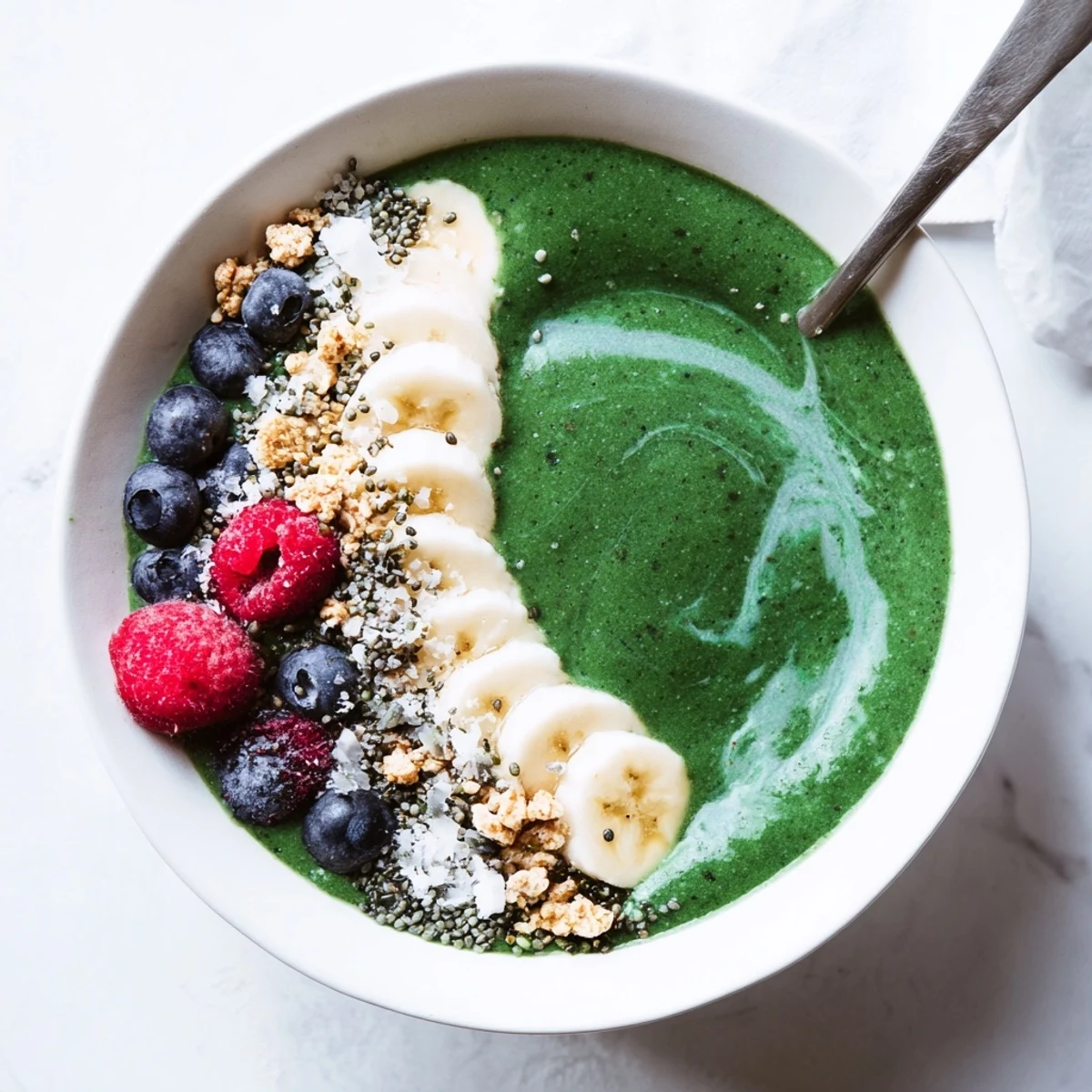 Creamy Green Smoothie Bowl topped with berries, crunchy granola, toasted coconut.