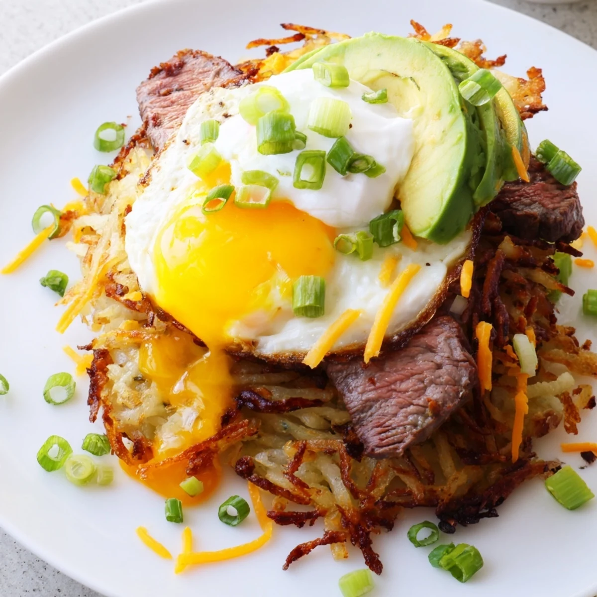 Close-up of Loaded Steak Egg Hash Brown Stacks Recipe: seared steak, melting cheddar  