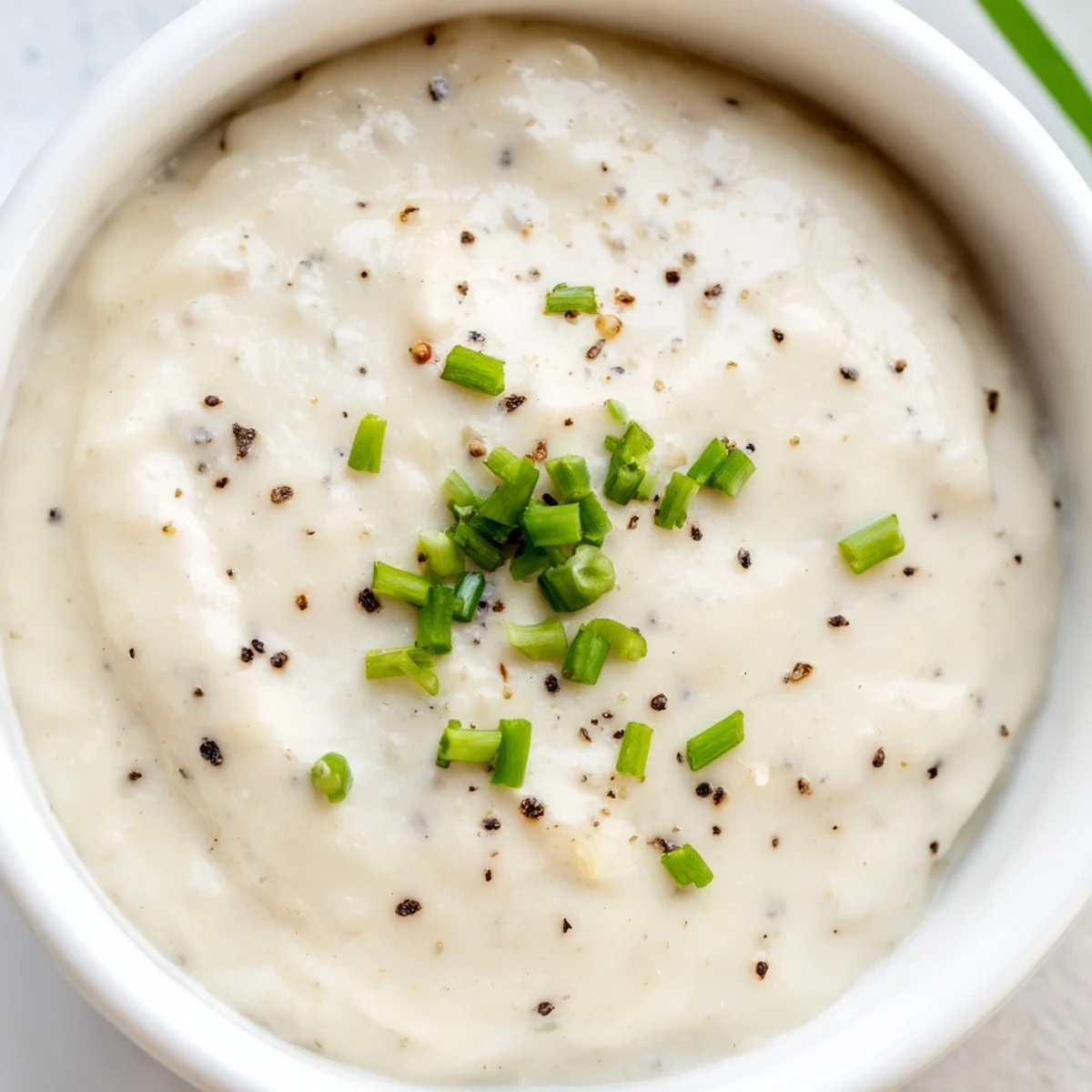 Smooth horseradish condiment dolloped beside roasted vegetables and dipping spoon
