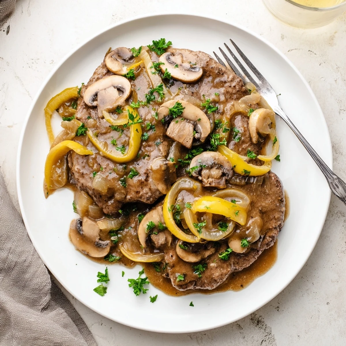 Golden brown Country Style Smothered Cube Steak served over mashed potatoes with rich onion mushroom gravy