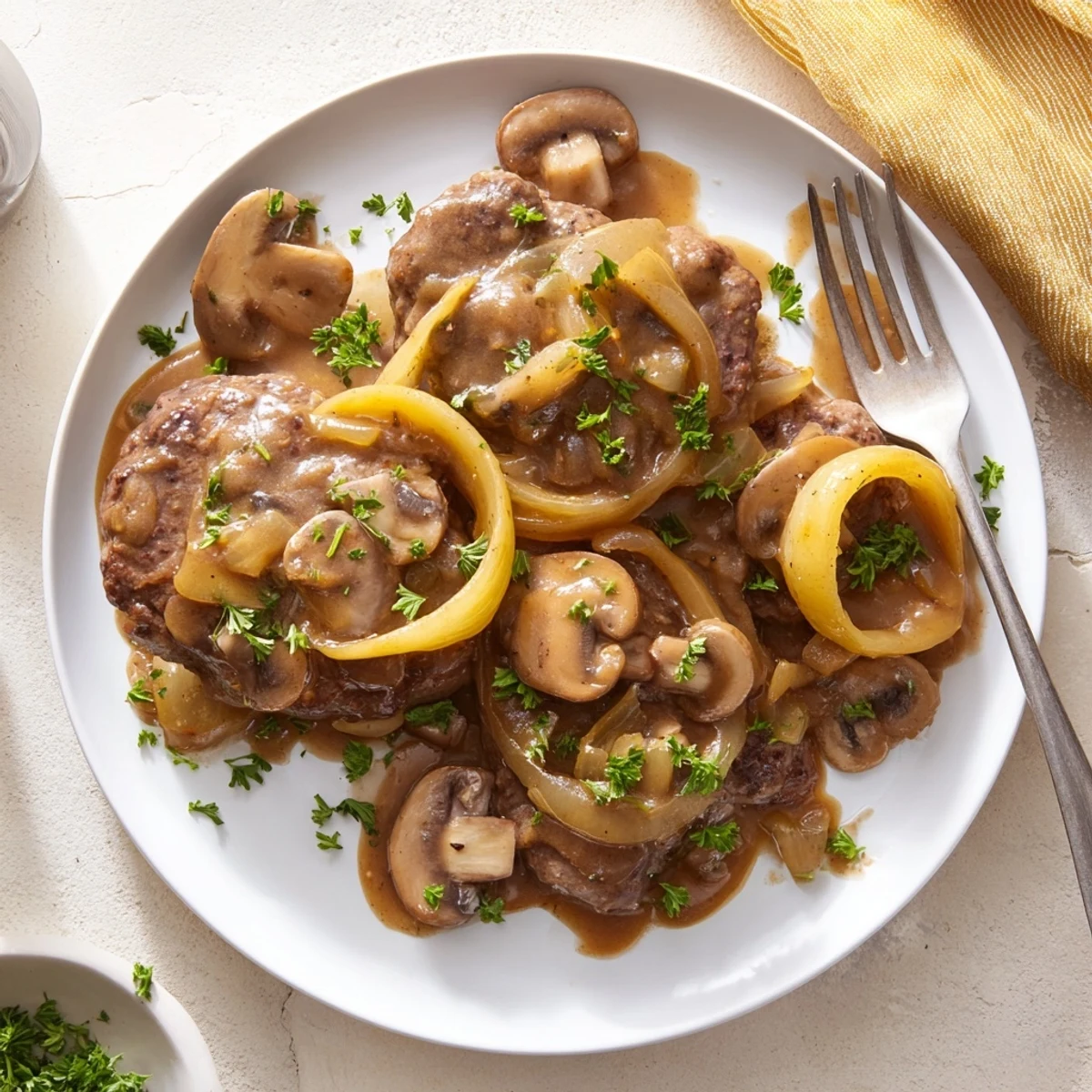 Tender beef cube steaks simmered in creamy brown gravy topped with fresh parsley and sliced mushrooms