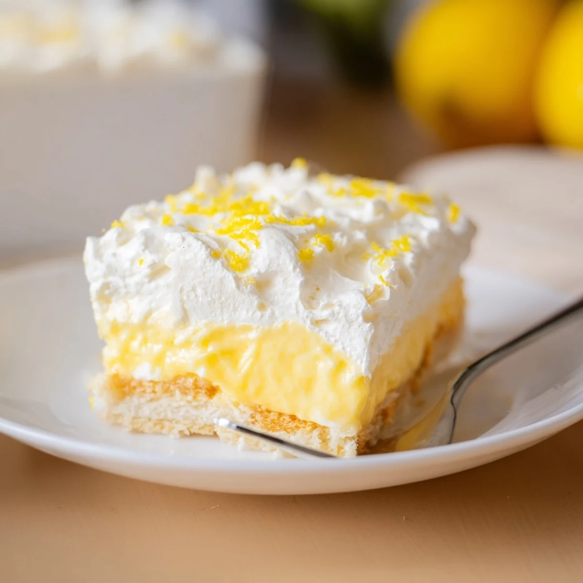 Creamy Lemon Lush Cake in white baking dish topped with whipped cream and citrus zest