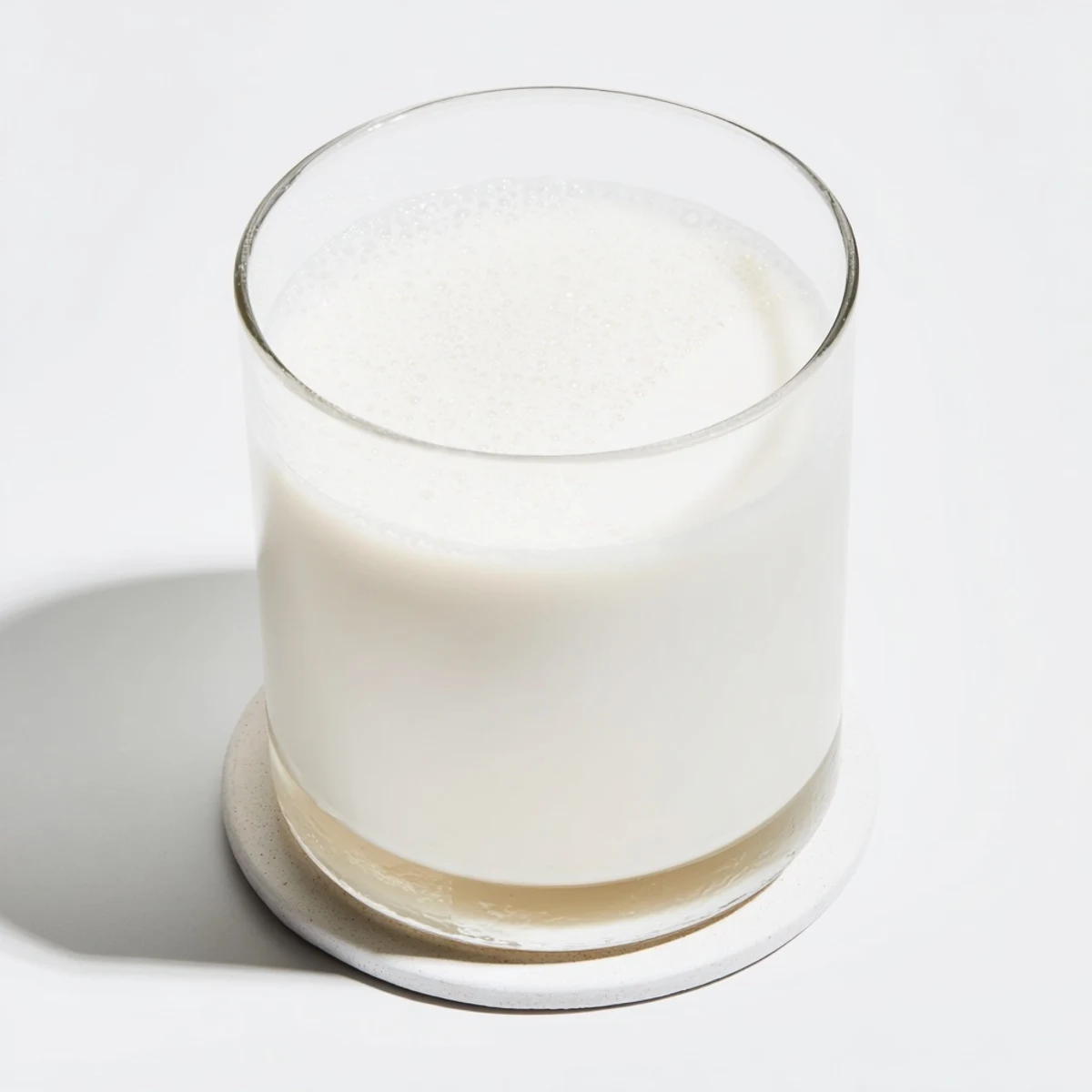 Creamy dairy-free almond milk in a mason jar with vanilla bean and scattered raw almonds