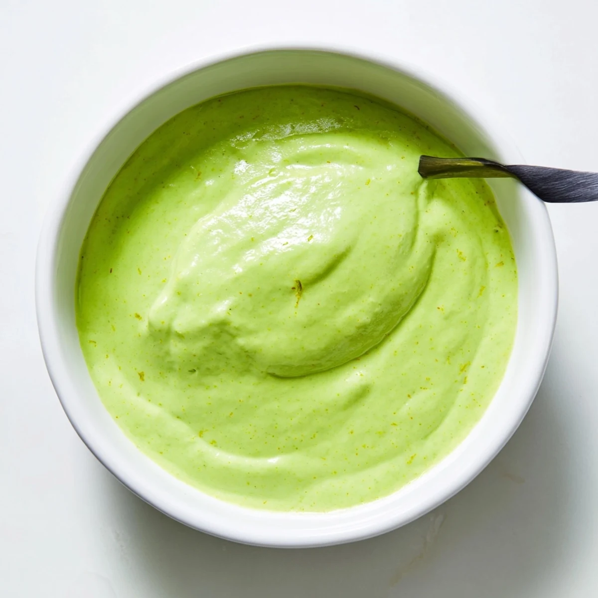 Vibrant green cilantro lime dipping sauce served in a small white bowl
