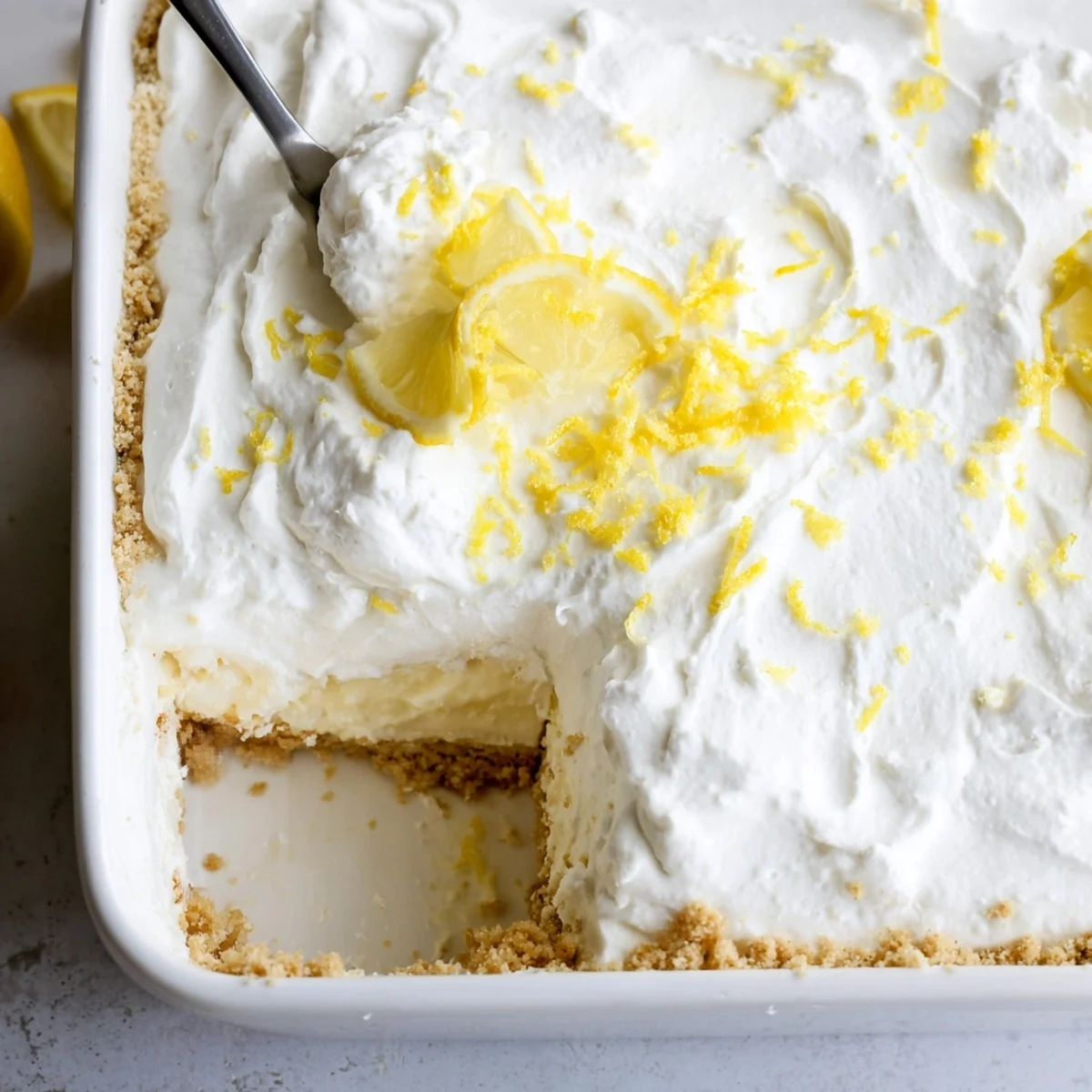 Slice of Lemon Lush Cake showing layered cream, tangy lemon, paired with tea