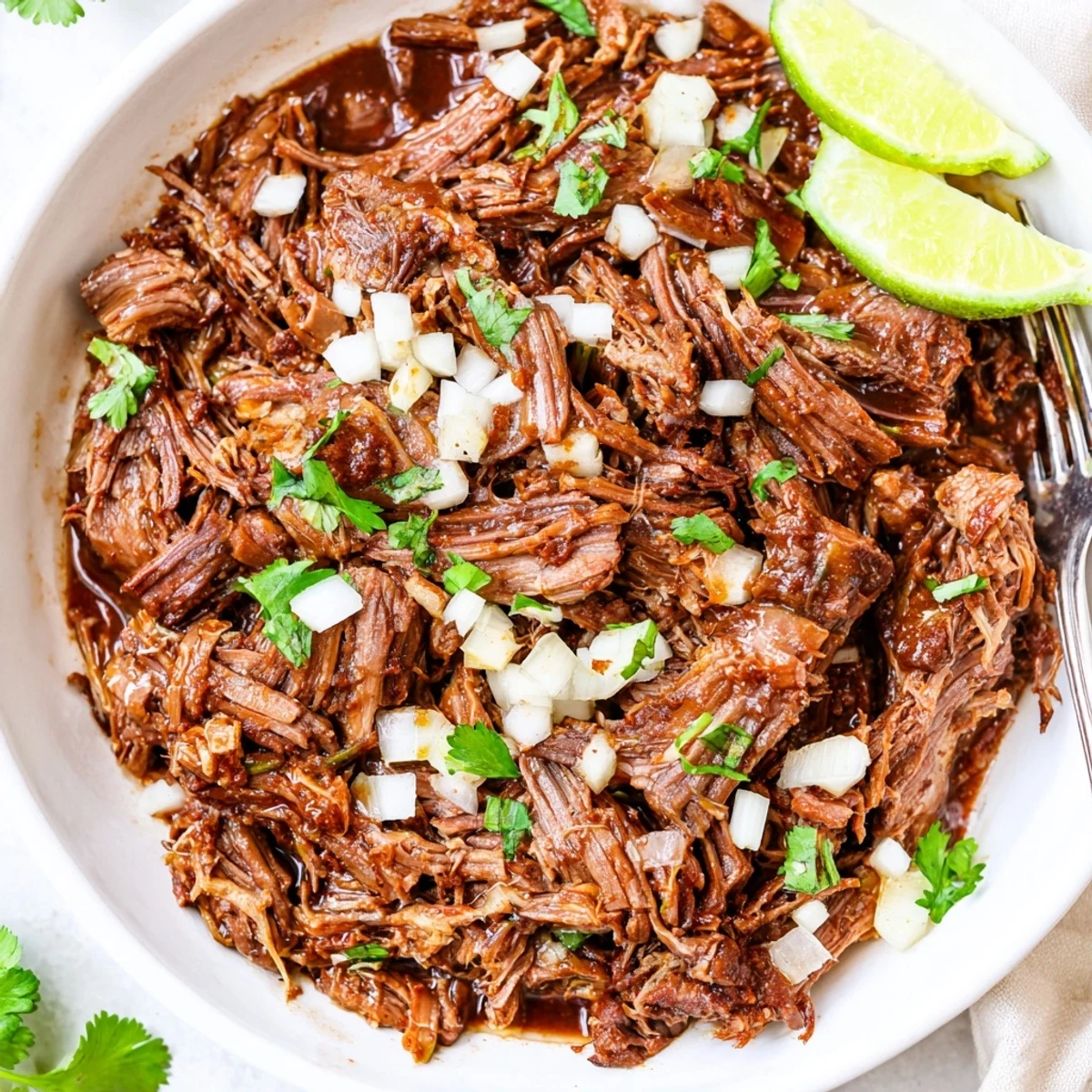 Slow Cooker Beef Barbacoa piled on warm tortillas with cilantro and lime