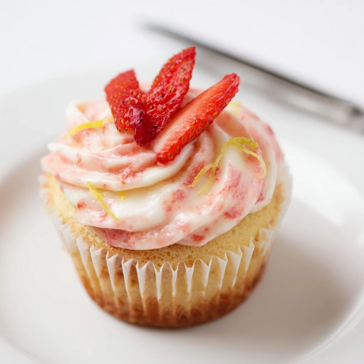 Plated Strawberry Lemonade Cupcakes beside sparkling lemonade, bright lemon aroma and berries