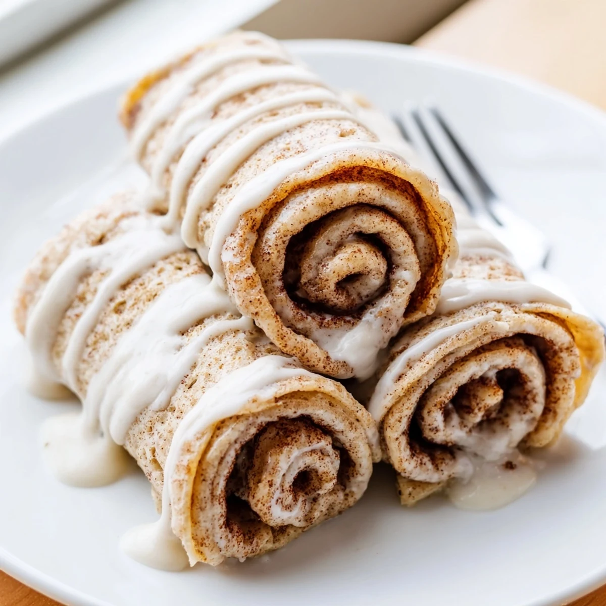 Rolled cinnamon roll protein crepes topped with luscious cream cheese glaze, served fresh and warm