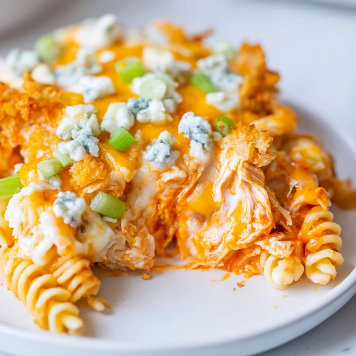 Golden baked Cheesy Buffalo Chicken Dip Casserole topped with blue cheese crumbles and green onions