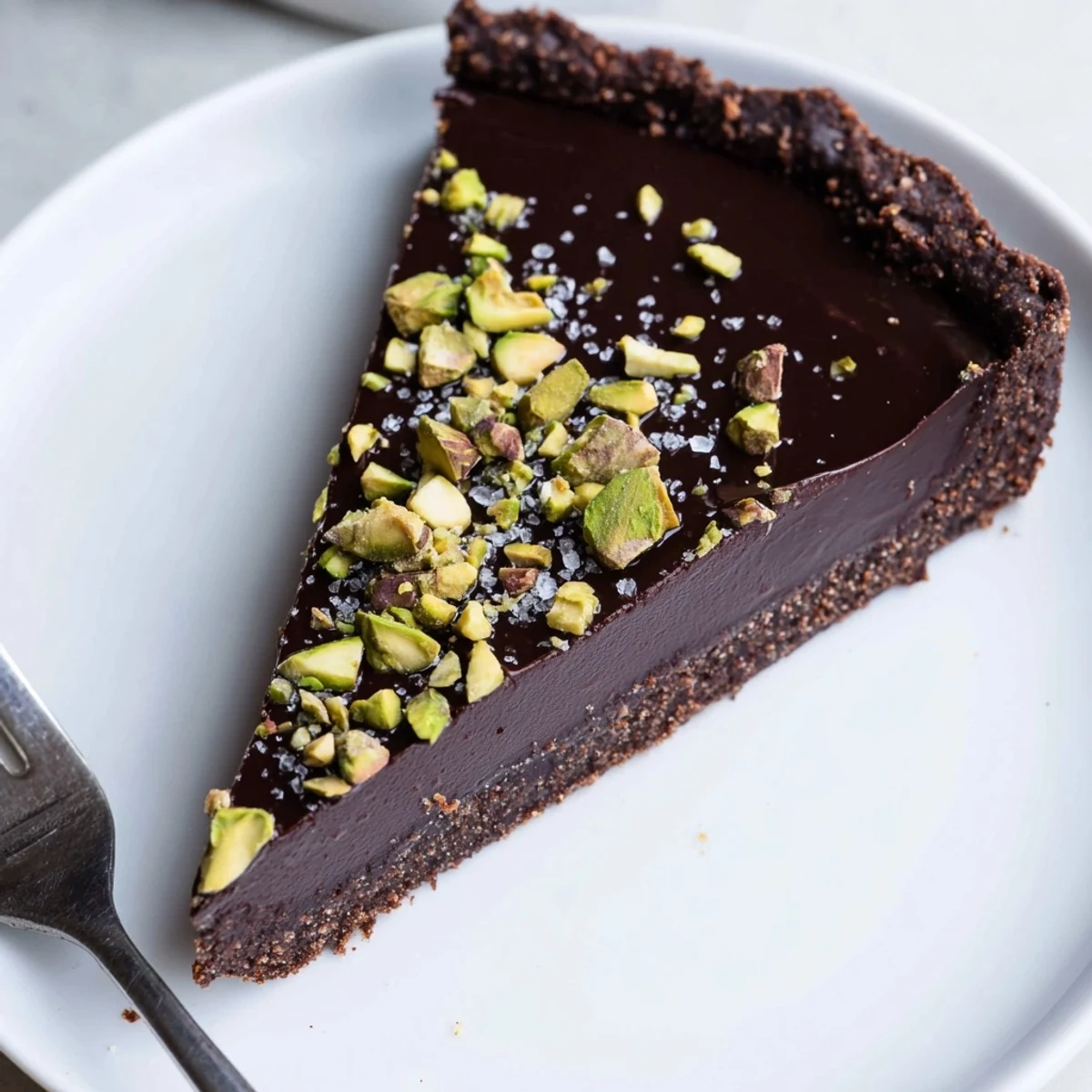 Dark Chocolate Pistachio Tart topped with crunchy green pistachios on a glossy ganache filling