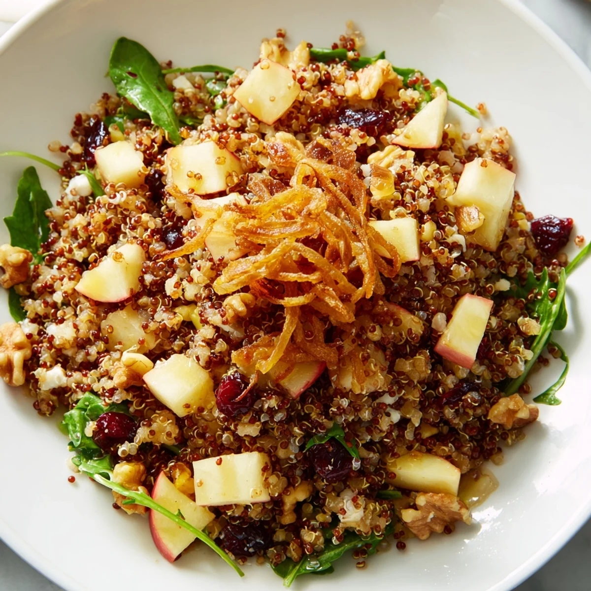 Honey Mustard Quinoa Apple Salad topped with golden crispy shallots on a rustic wooden serving bowl