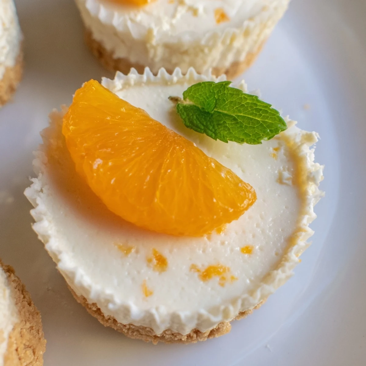 Golden graham cracker crust cups filled with zesty mini no bake orange cheesecakes batter