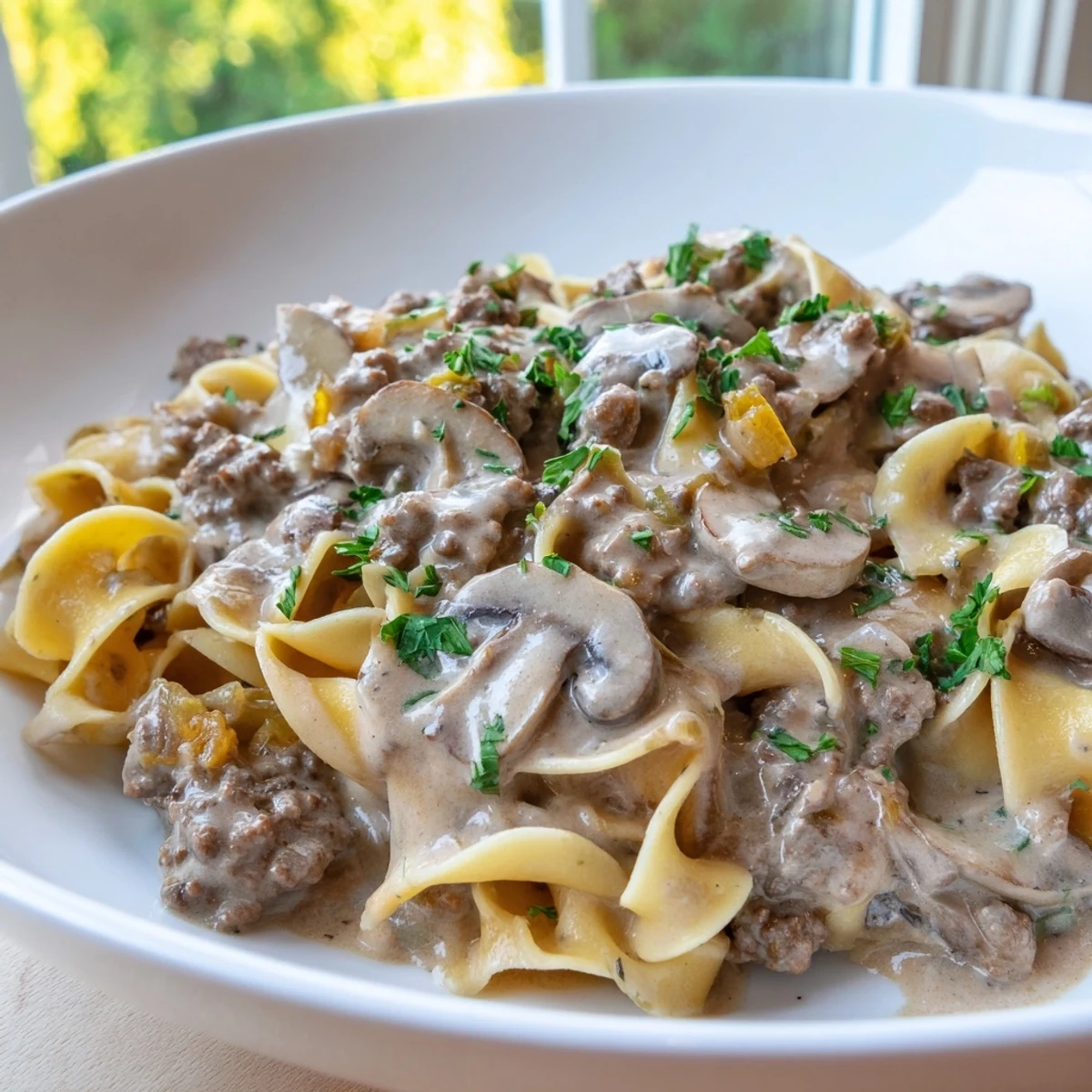 Creamy hamburger stroganoff served over tender egg noodles with fresh parsley garnish