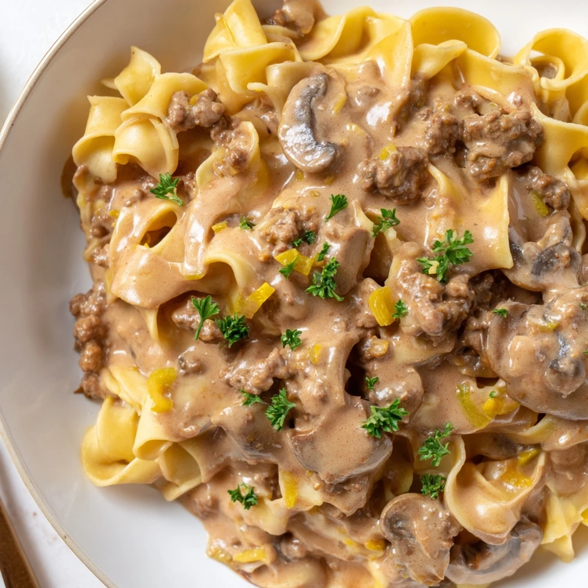 Steaming bowl of hamburger stroganoff with golden ground beef and velvety sauce