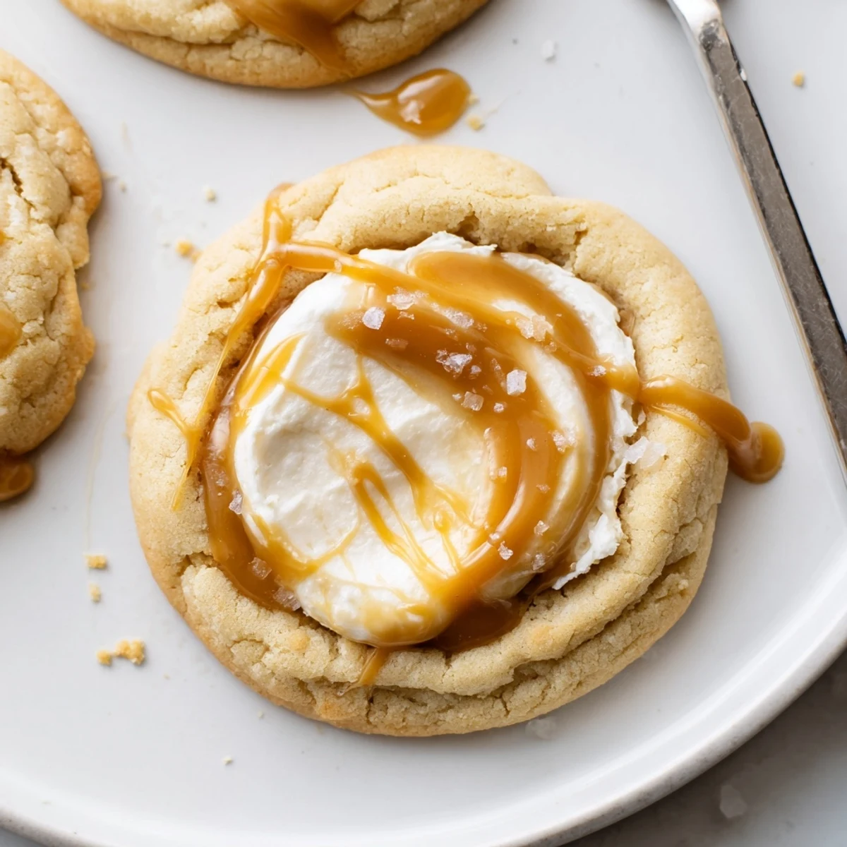 Soft caramel cheesecake cookies with golden caramel drizzle on a rustic baking sheet