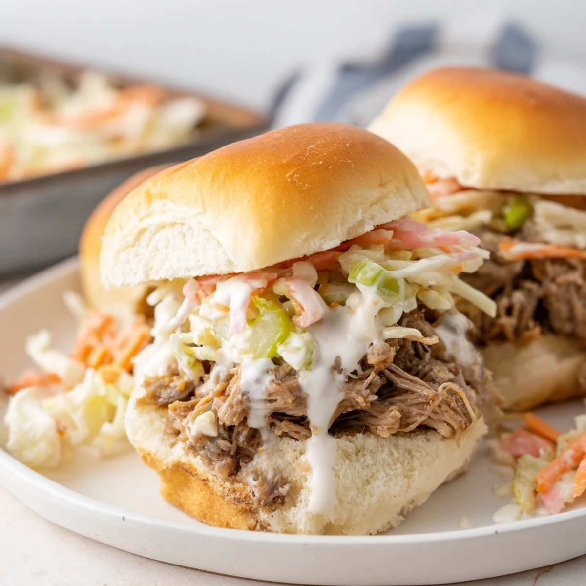Golden slider buns piled high with saucy Alabama white sauce pulled lamb and crisp cabbage slaw