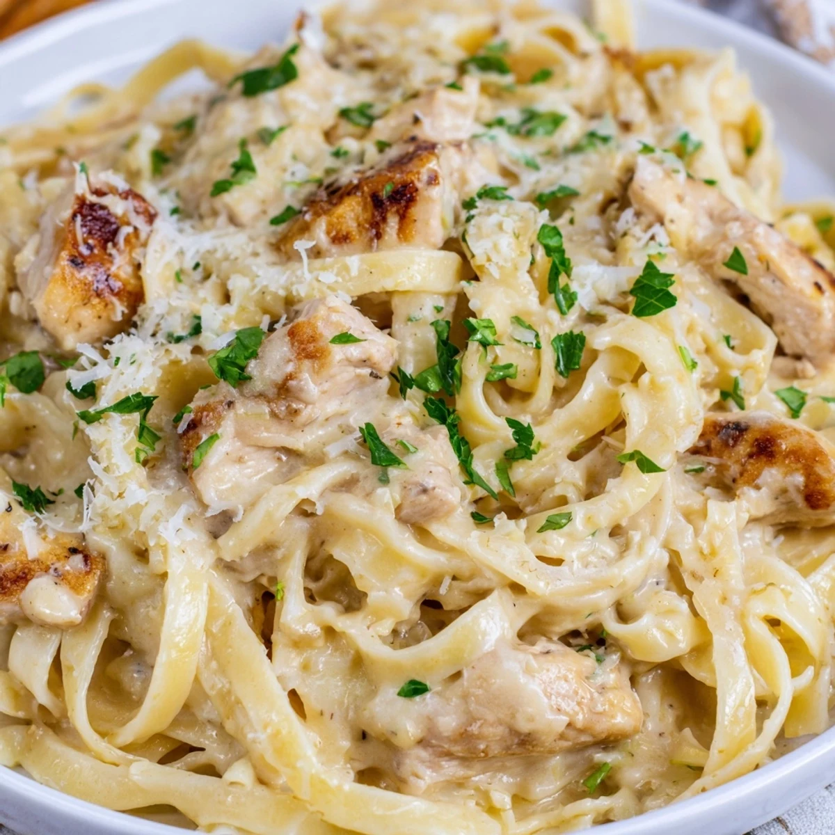 Creamy garlic Parmesan chicken pasta topped with fresh parsley and extra cheese