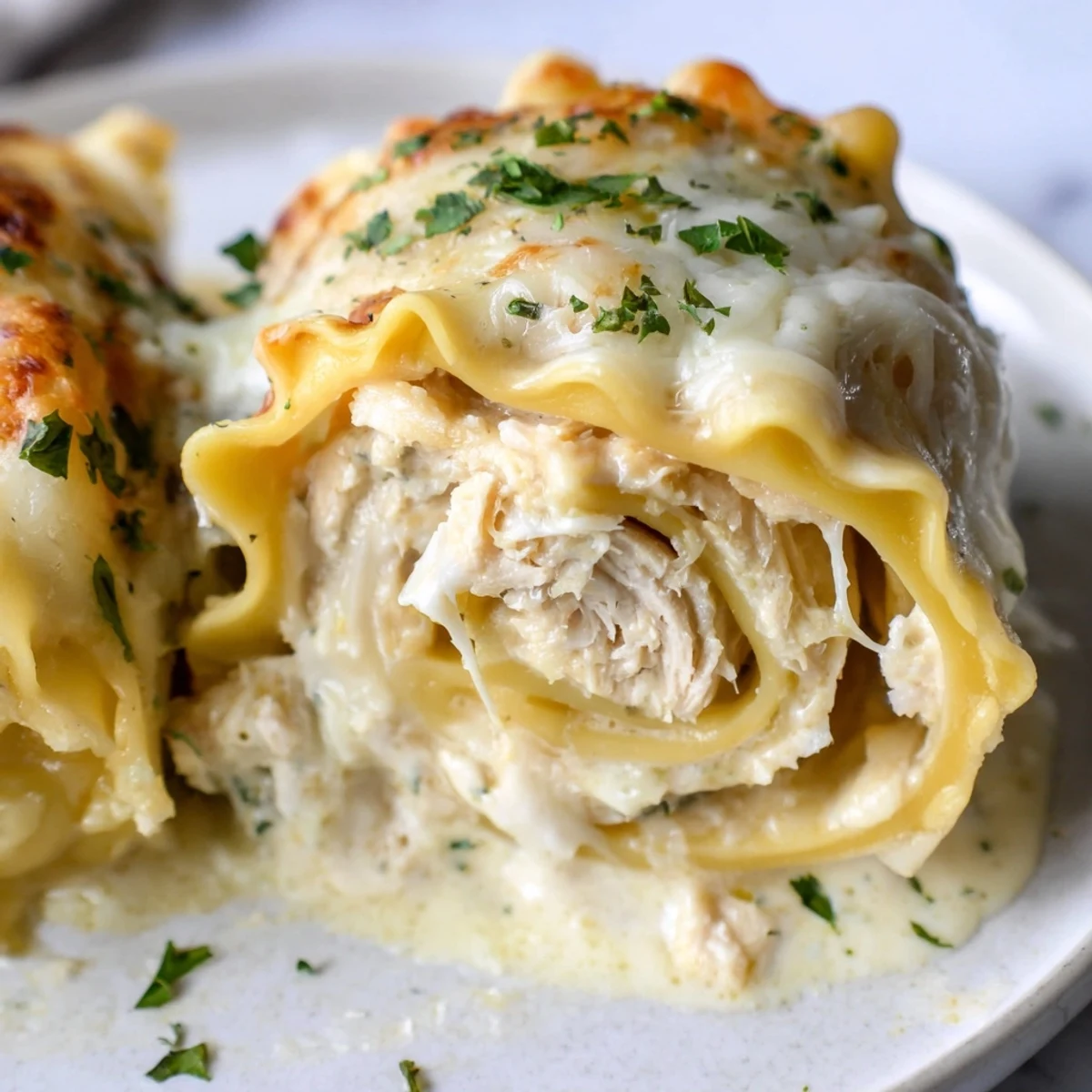 Golden bubbling garlic Parmesan chicken lasagna roll ups smothered in creamy béchamel sauce