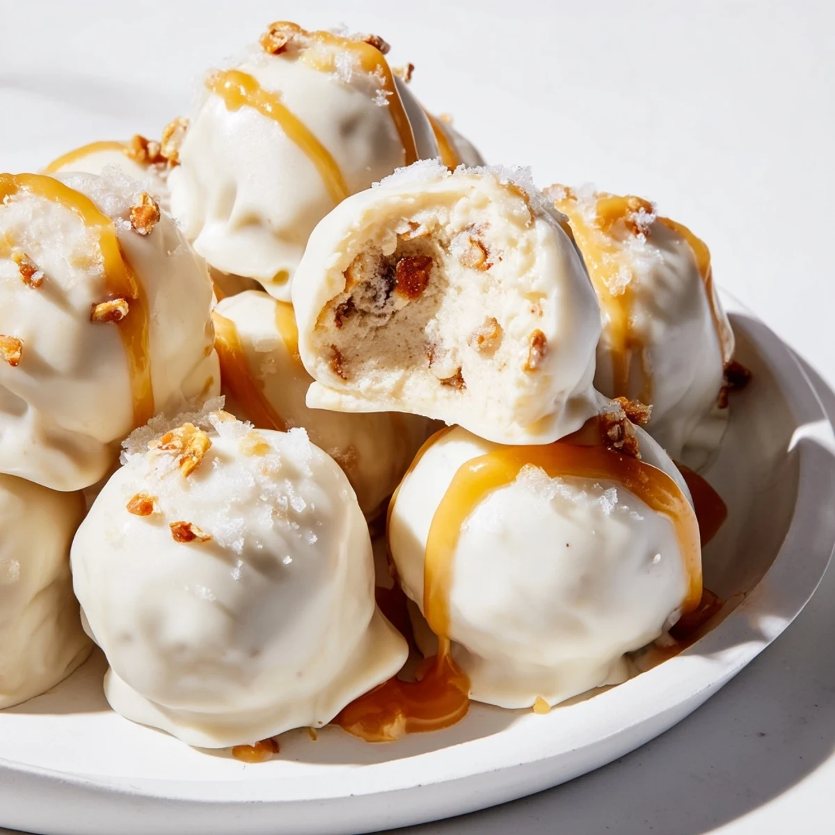 Golden-dipped salted caramel pretzel cheesecake balls coated in crushed pretzels and flaky salt