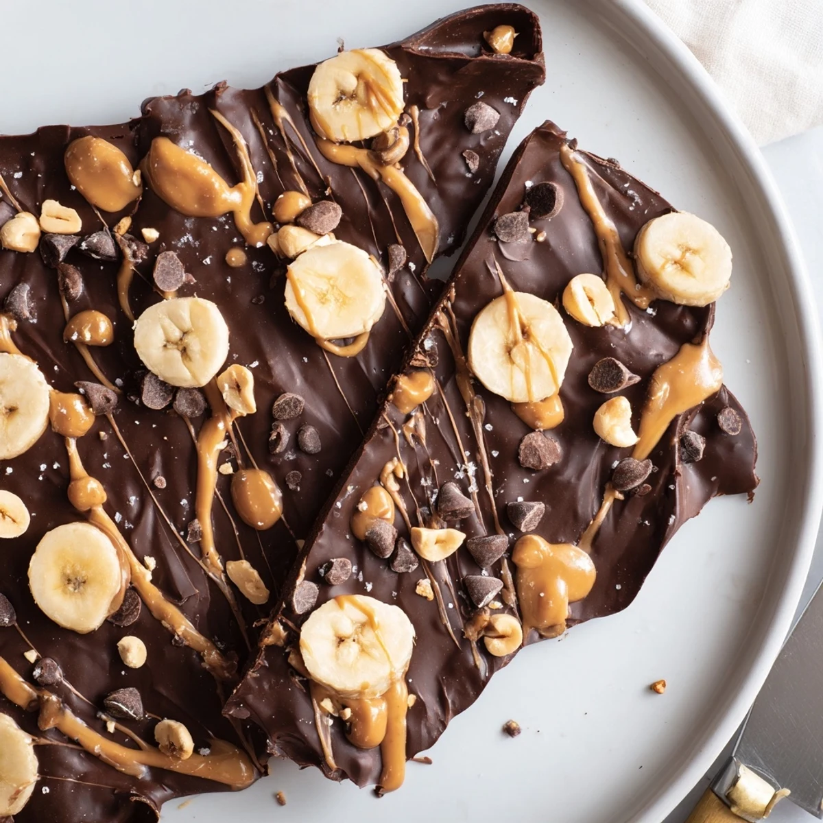 Glossy chocolate banana bark broken into rustic shards dotted with roasted almonds
