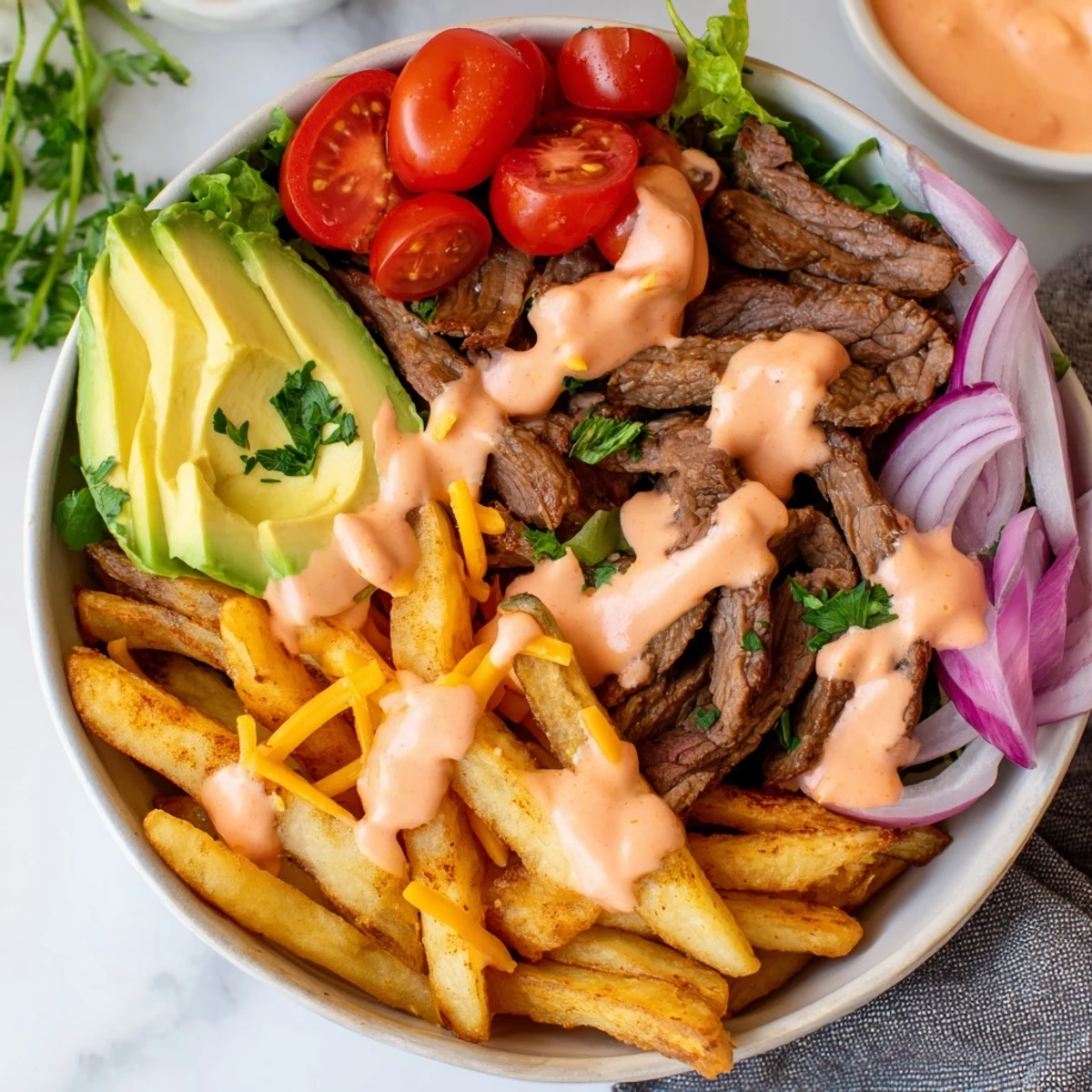 Juicy steak strips and crispy fries bowl loaded with fresh vegetables and zesty sauce