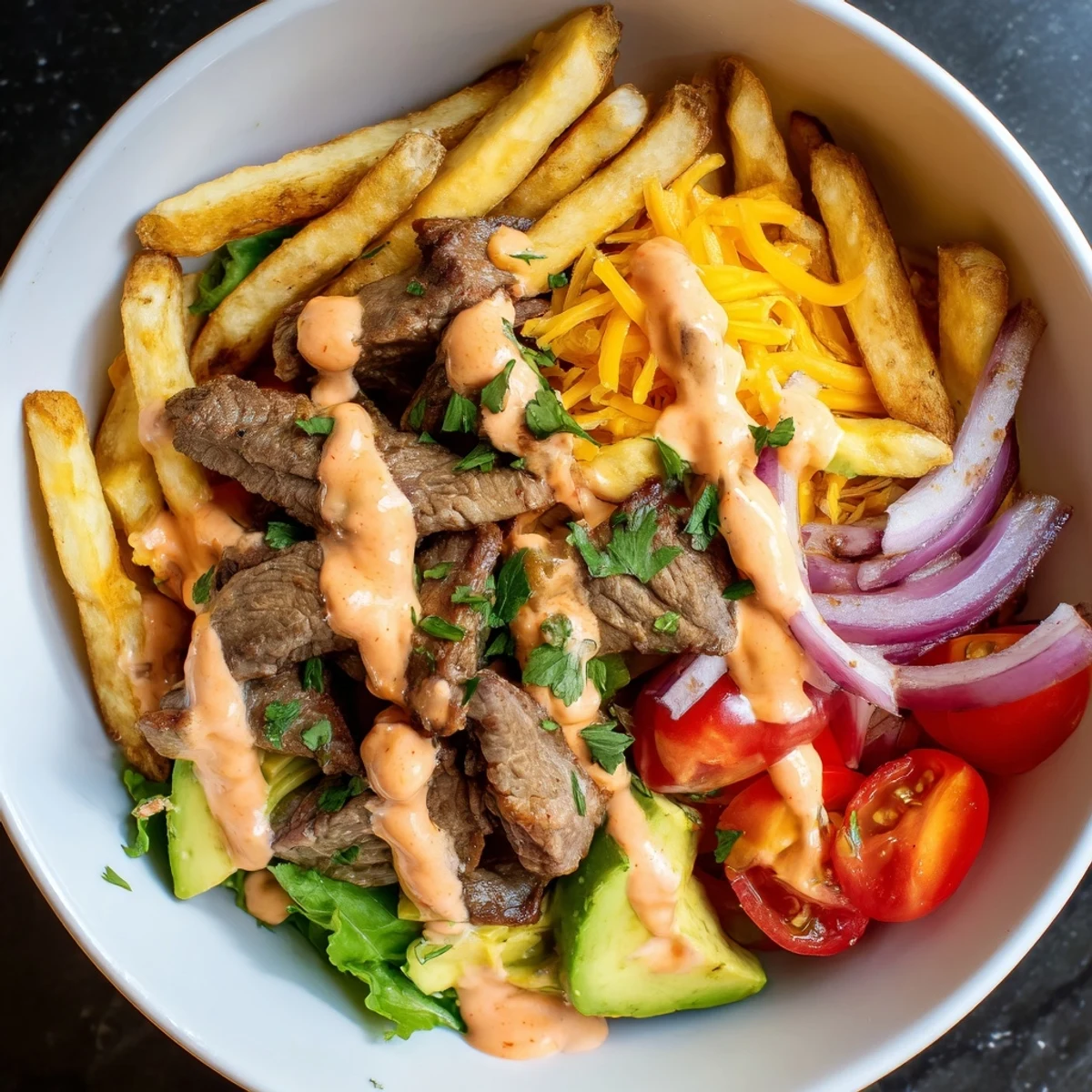 Steak strips crispy fries bowl topped with creamy avocado and melted cheddar cheese