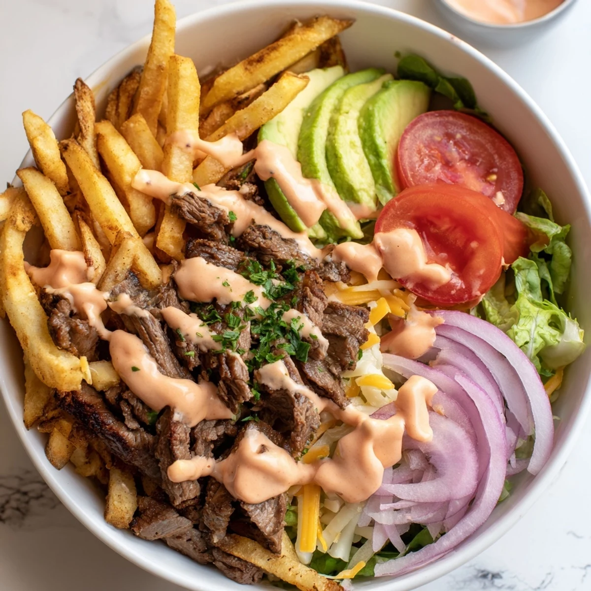 Golden crispy fries bowl featuring seared steak strips, ripe tomatoes, and smoky drizzle