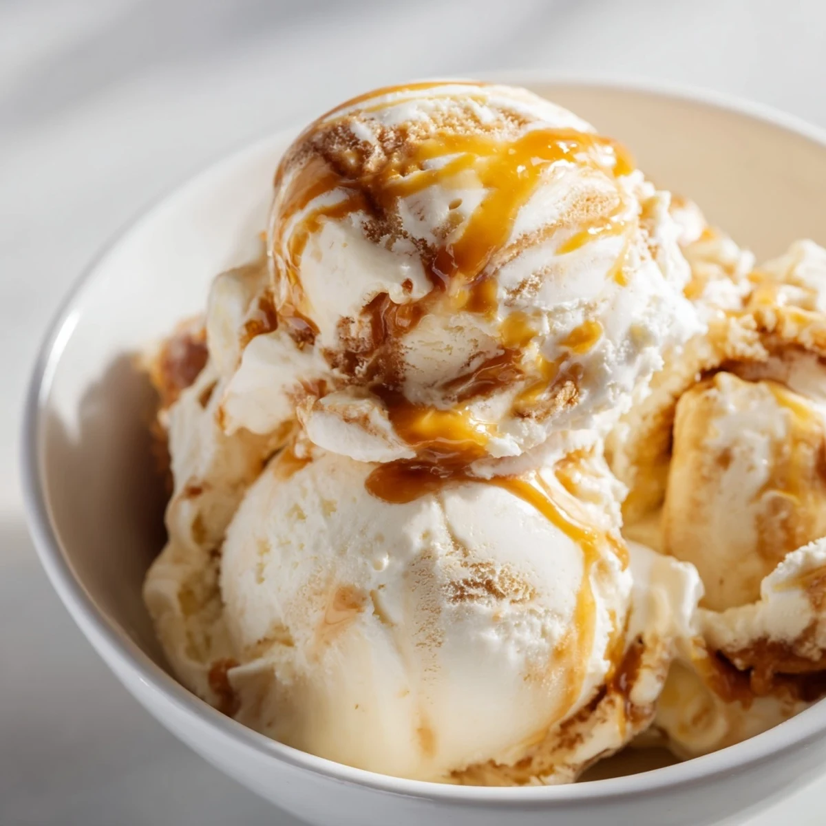 Rich no churn salted caramel ice cream served in a bowl with drizzle.  