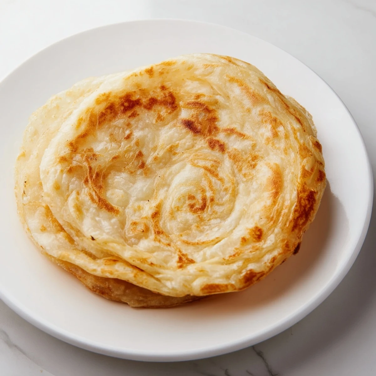 Golden flaky Roti Canai flatbread layered with butter and served warm.  