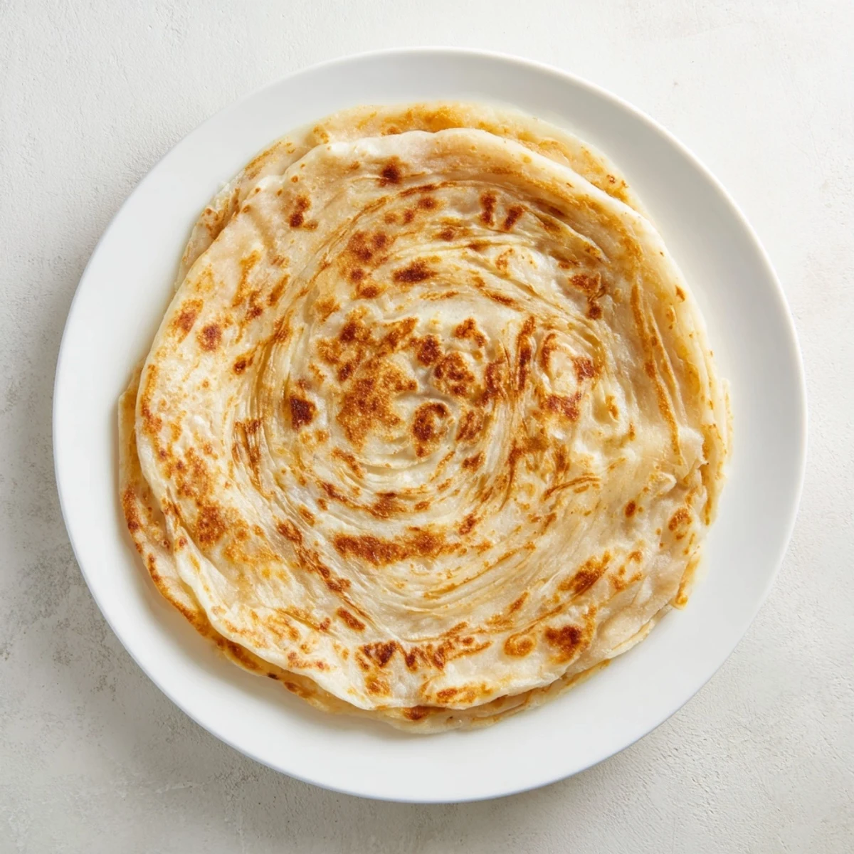 Homemade Malaysian Roti Canai with golden brown spots and a soft texture.