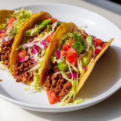 A close-up view of fully loaded Beef Tacos with homemade seasoning, featuring creamy avocado slices, fresh cilantro, and a dollop of sour cream.