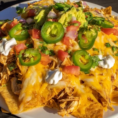 This loaded Pulled Chicken Nachos platter is baked until bubbly and topped with cool sour cream and lime wedges for serving.