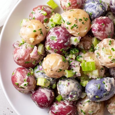 Festive red white blue potato salad topped with fresh chives and parsley